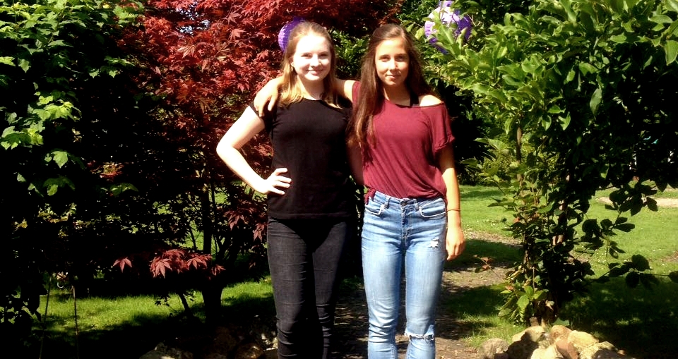 Noa und Celia stehen in einem Garten.